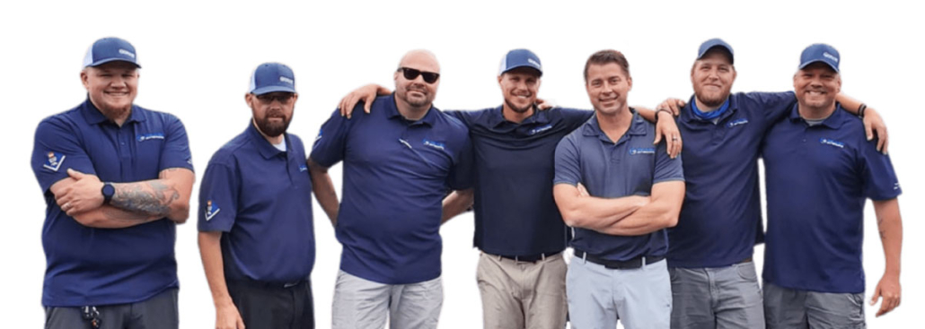 A group of men in blue shirts posing for a photo during a roofing replacement project.