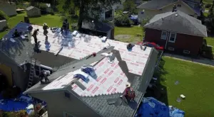 An aerial view of people working on Revived Exteriors' roof.