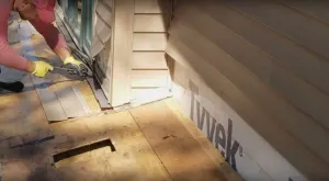 A man is working on reviving a wooden deck.