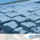 The snow-covered roof, showing visible wear and tear, hints at the relentless Illinois winters. The Revived Exteriors logo sits in the bottom corner, symbolizing a commitment to durable roofing materials and thermal efficiency.